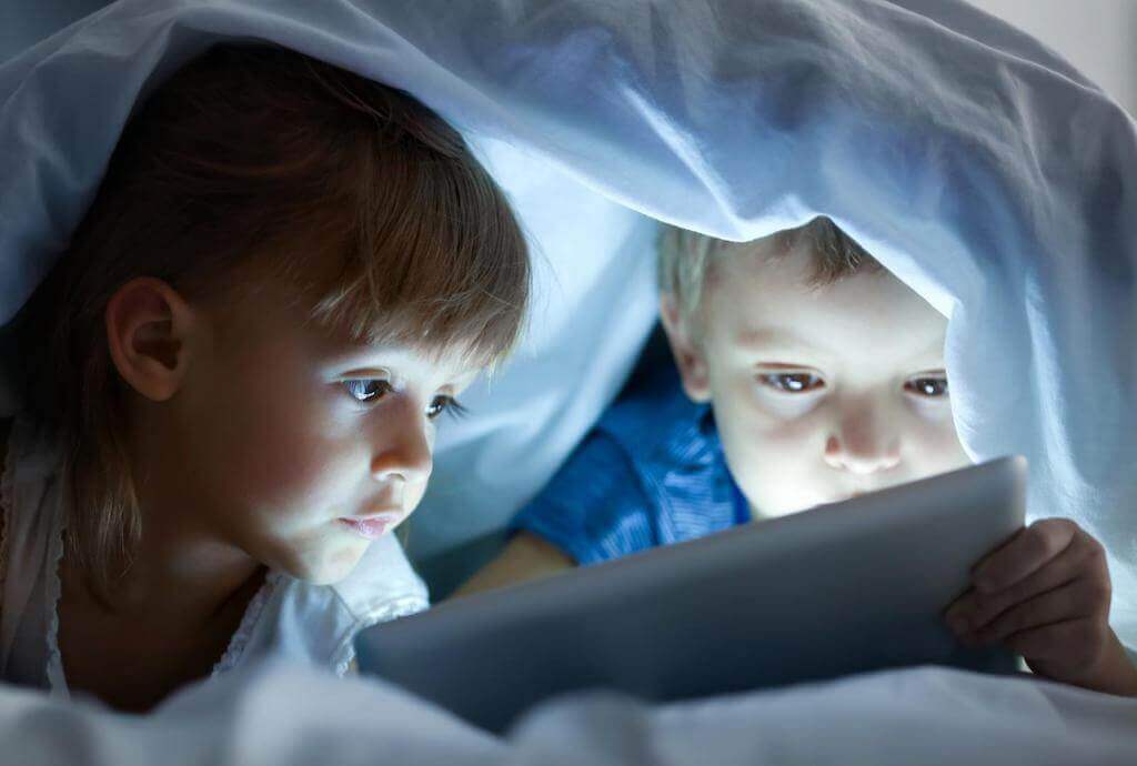 Zwei Kinder im Bett mit Tabletjpeg